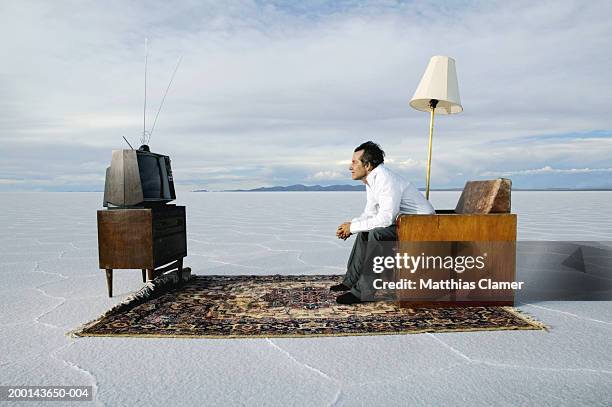 mature man watching television on salt flat, side view - man sitting in chair stock pictures, royalty-free photos & images