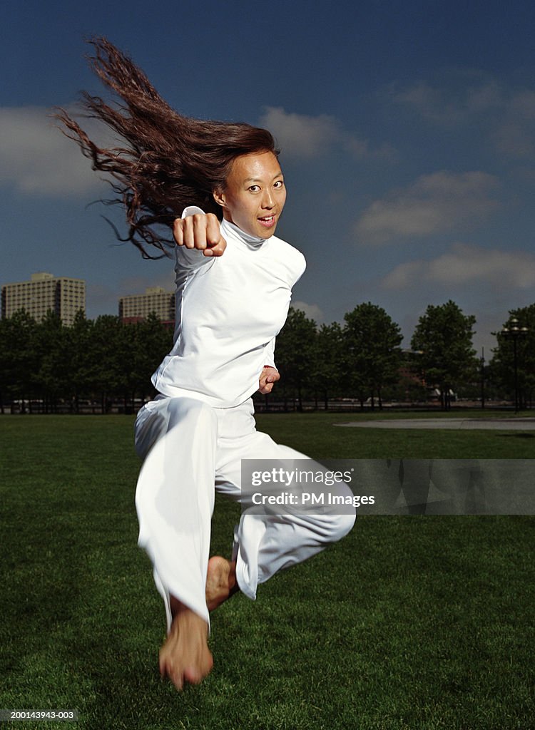 Woman practicing tae kwon do in park (blurred motion)