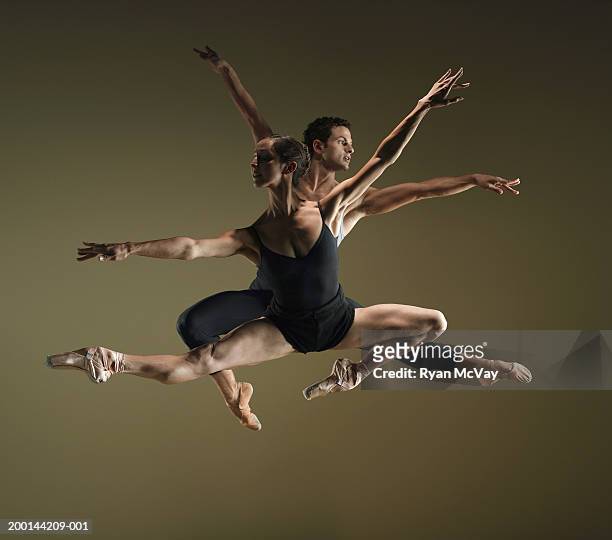 male and female ballet dancers in mid air poses, arms extended - arabesque stockfoto's en -beelden