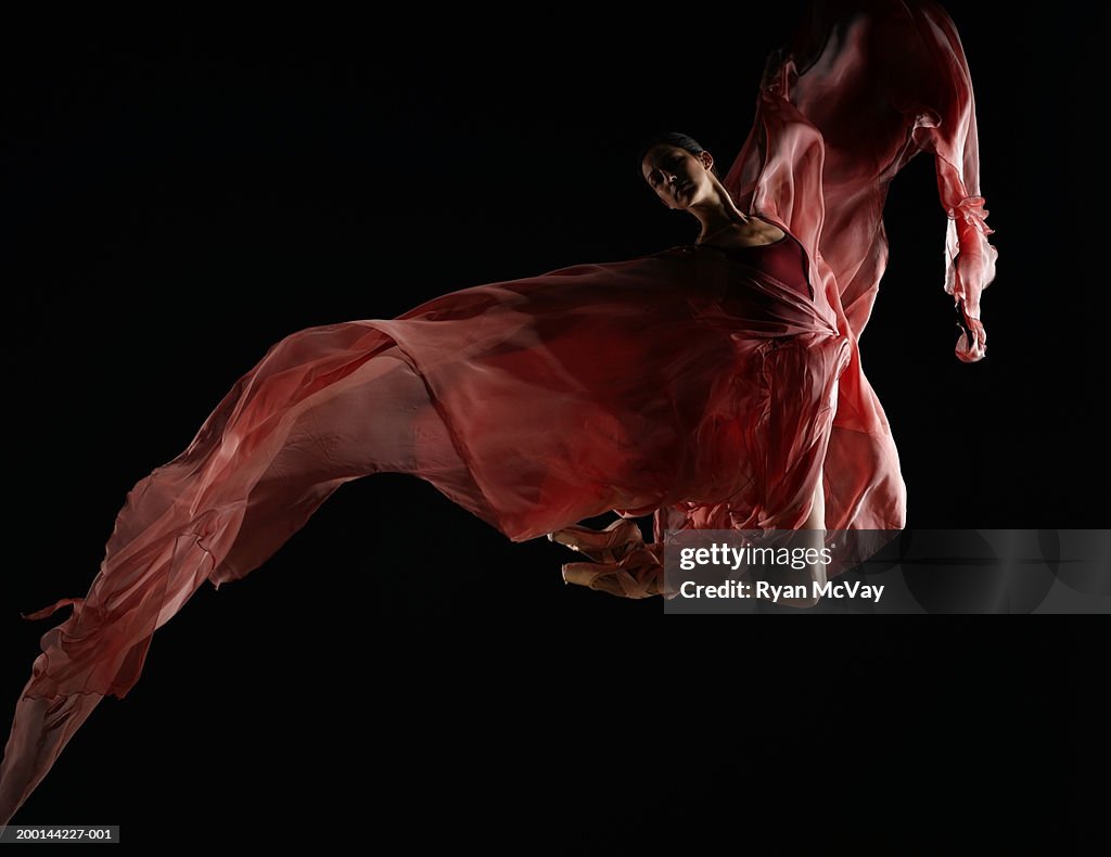 Ballet dancer wearing flowing dress in mid air leap