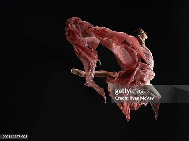 ballet dancer wearing flowing dress in mid air leap, side view - ballett imagens e fotografias de stock