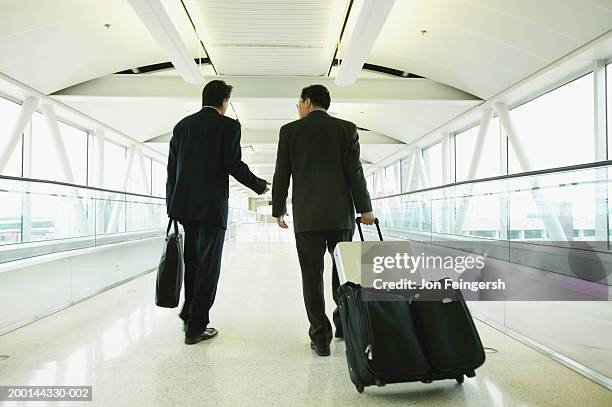 businessmen on motorized walkway in airport talking, rear view - 日本人　空港 ストックフォトと画像