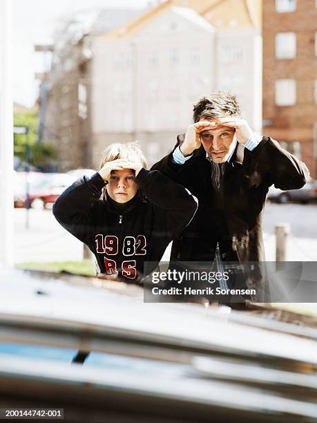 father and son (9-11) peering through window at car - car top view photos et images de collection