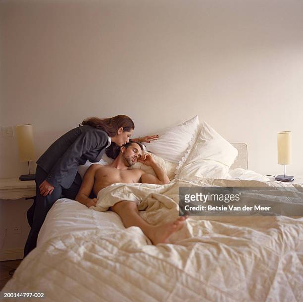 mature woman kissing young man lying in bed on head - role reversal stock-fotos und bilder