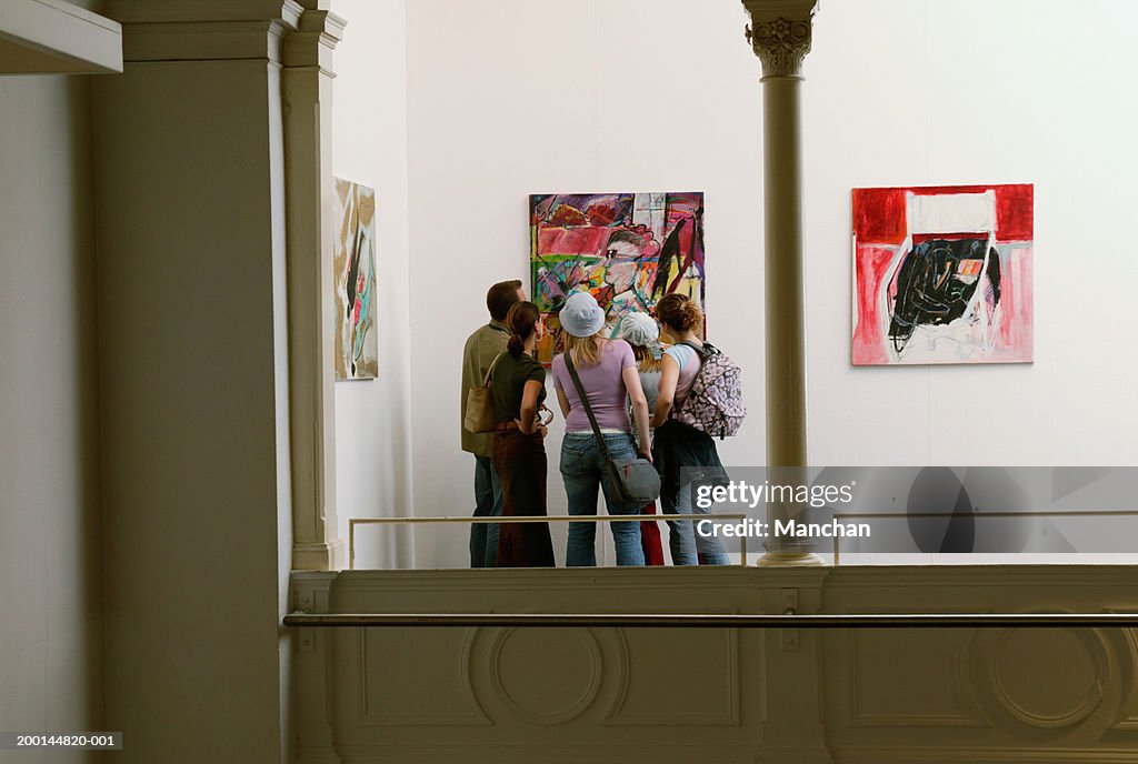 Group of people looking at painting in gallery, rear view