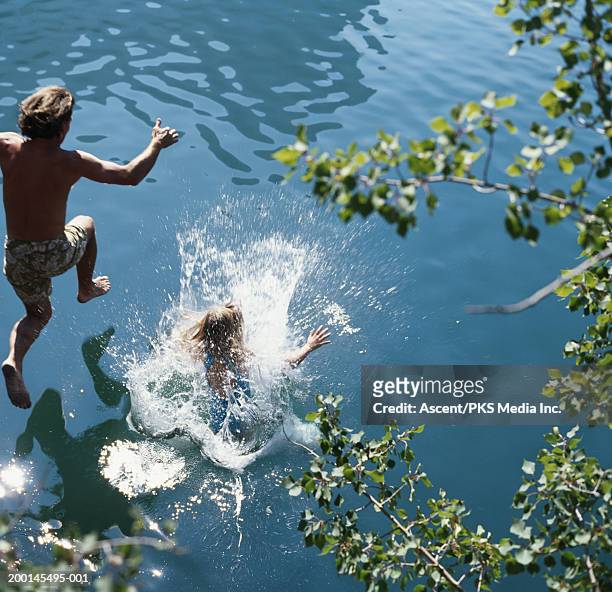 father and daughter (7-9) jumping into lake, rear view - cannonball diving stock-fotos und bilder