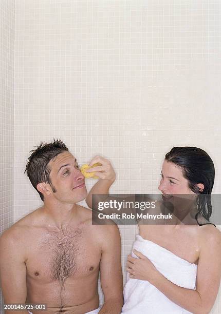 woman wiping man's face with sponge in steam room - couples showering 個照片及圖片檔