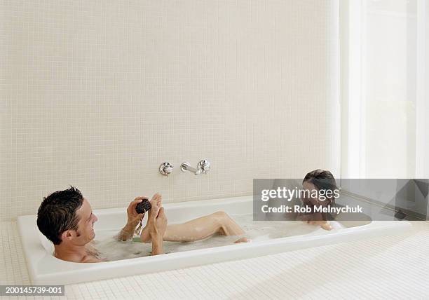 man scrubbing woman's foot with pumice stone in bubblebath - couple bathtub - fotografias e filmes do acervo