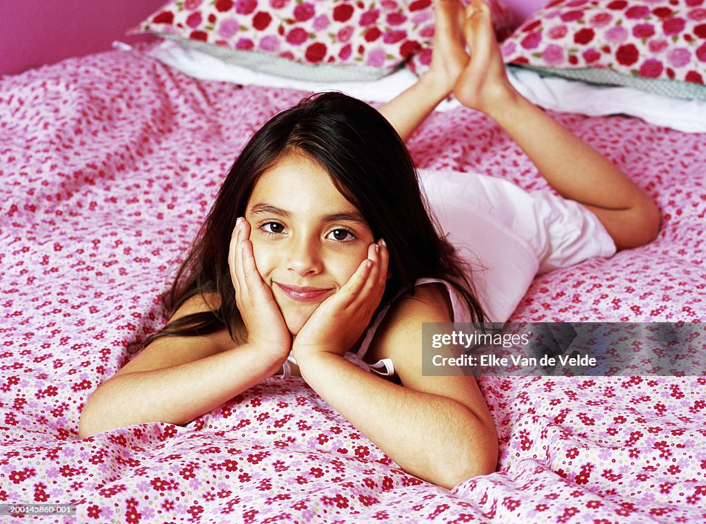 Girl (5-7) lying on bed, portrait