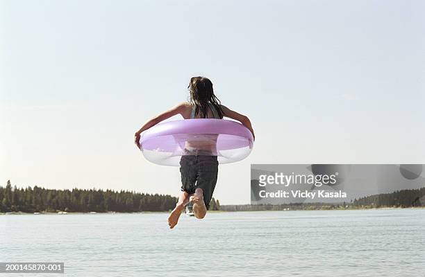 girl (11-13) jumping into lake with inner tube, rear view - 13 year old girls in shorts stock pictures, royalty-free photos & images