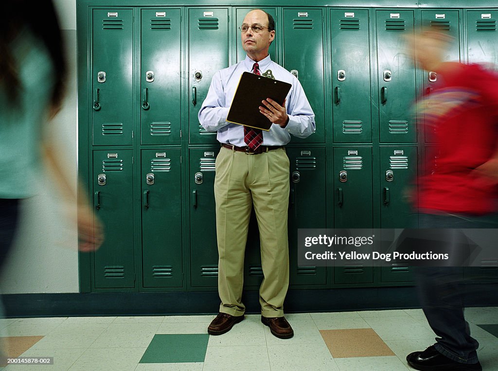 Man in school hallway with clipboard