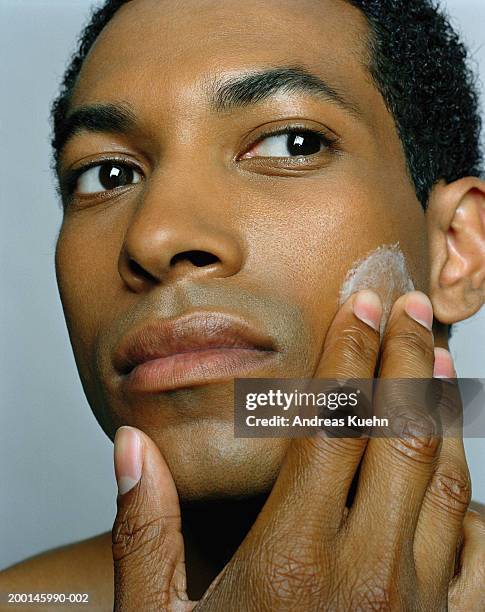 young man applying moisturizer to face, close-up - guy with face in hands stockfoto's en -beelden