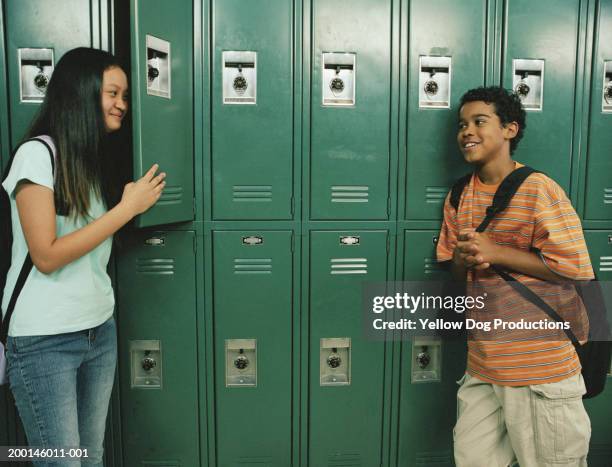 students (12-14) near lockers, smiling - shy stockfoto's en -beelden