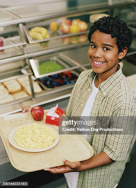 boy (12-14) holding tray with food in cafeteria, smiling, portrait - school lunch foto e immagini stock