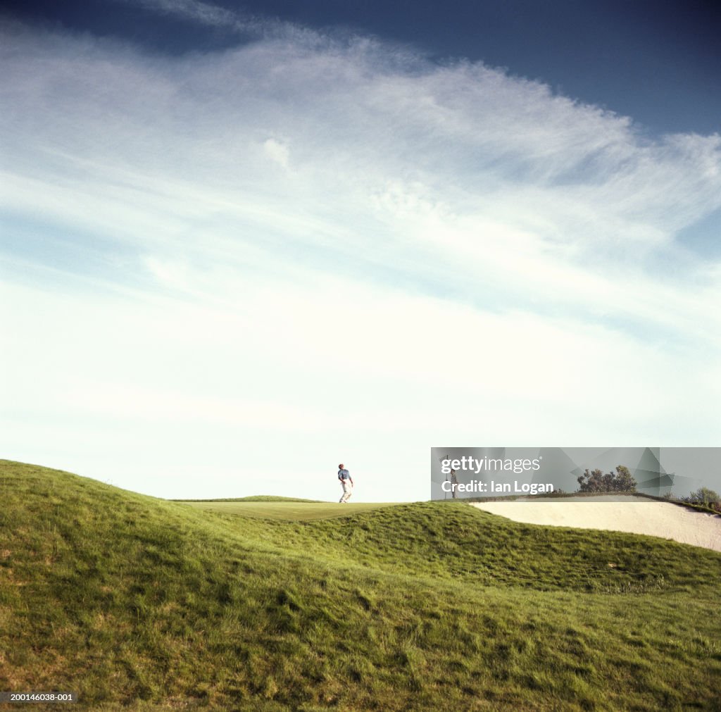 Two men playing golf, one man holding flag