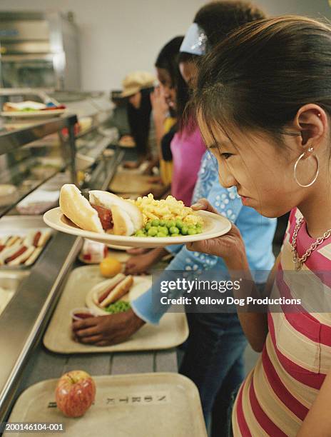 girl (12-14) on lunch line frowning at food, side view - offensive stock-fotos und bilder