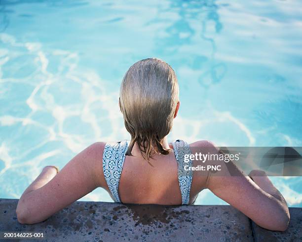 woman leaning on edge of swimming pool, rear view - spa treatment photos et images de collection