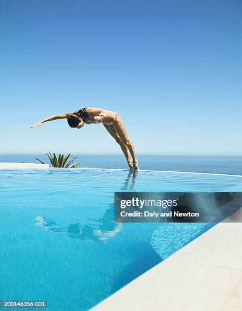young woman diving into swimming pool - taking the plunge stock-fotos und bilder
