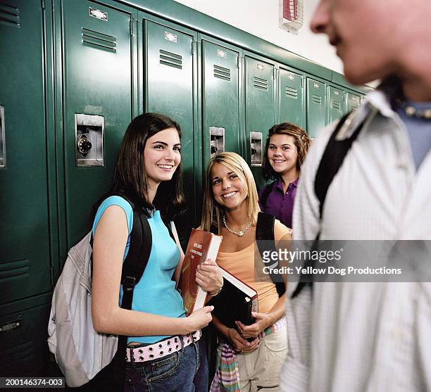 teenage girls (16-18) standing near locker, looking at boy, smiling - male with group of females stock pictures, royalty-free photos & images