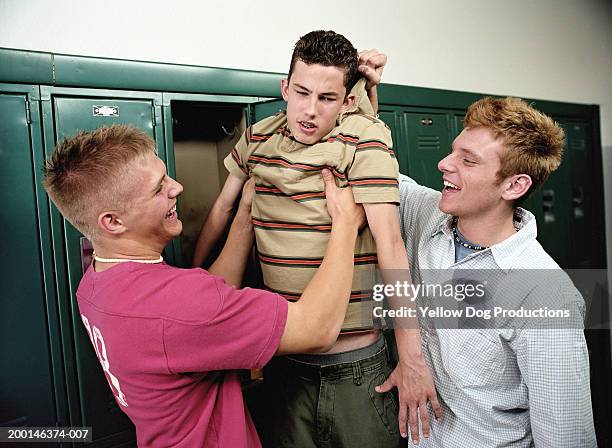 teenage boys (16-18) bullying younger boy - violencia escolar fotografías e imágenes de stock