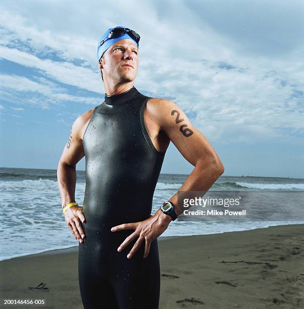 triathlete standing on beach, wearing wetsuit - triathlet stock-fotos und bilder