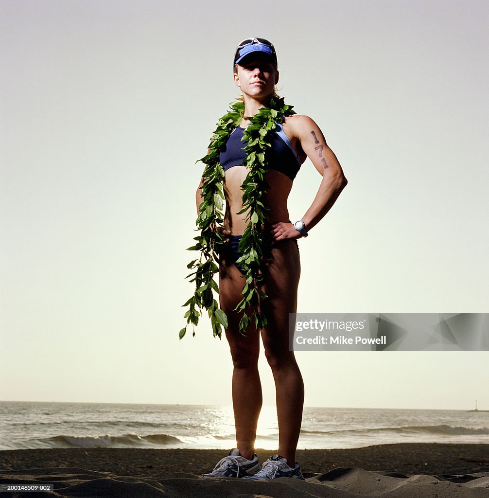 Triathlete wearing ti leaf lei, standing on beach, portrait