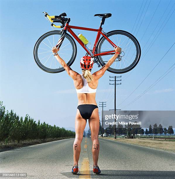 triathlete standing in middle of road, holding bicycle over head - orthographic symbol stock pictures, royalty-free photos & images