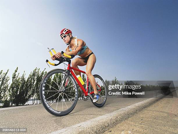 triathlete riding bicycle down road in triathlon - triathlon cycling stock pictures, royalty-free photos & images