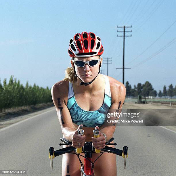 triathlete on bicycle, standing in middle of road, portrait - triathlete stockfoto's en -beelden