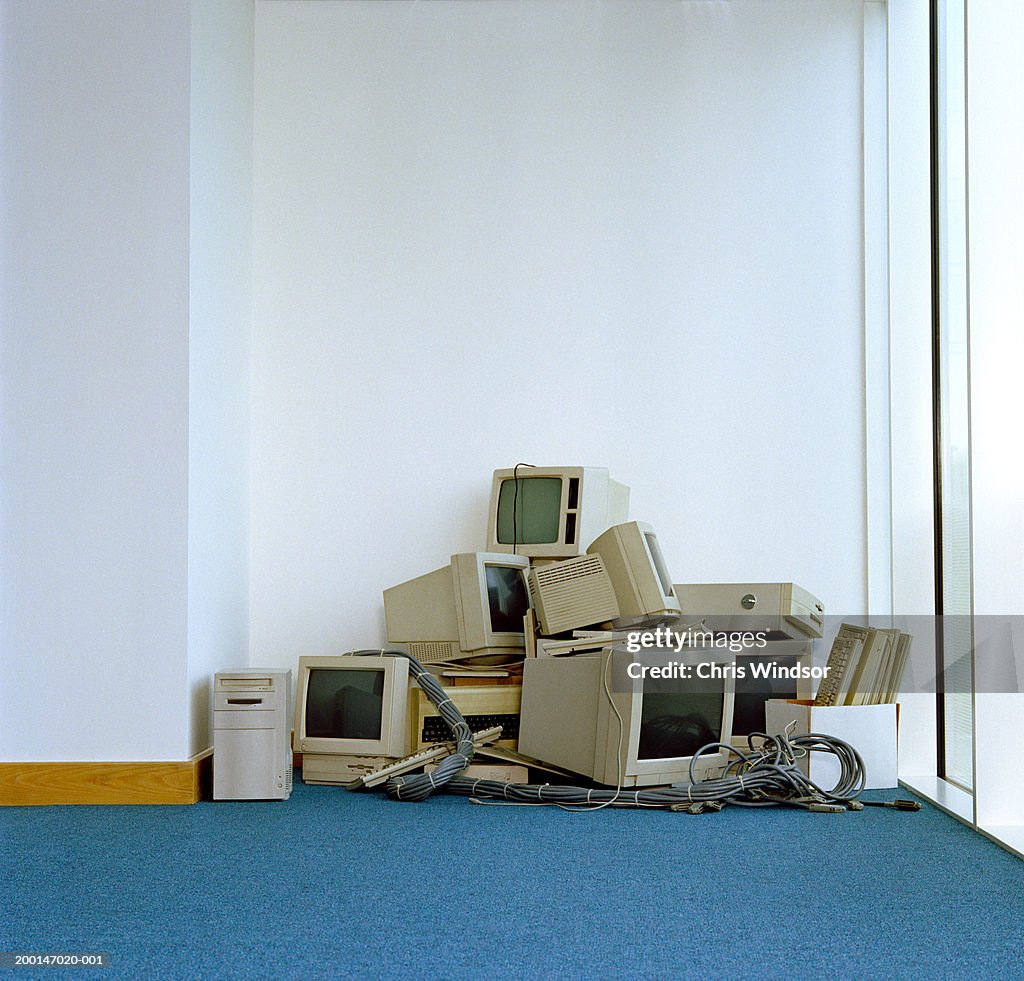 Pile of computer equipment in corner of office