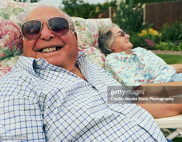 senior couple relaxing on garden chairs (focus on man in foreground) - couple de vieux drole photos et images de collection