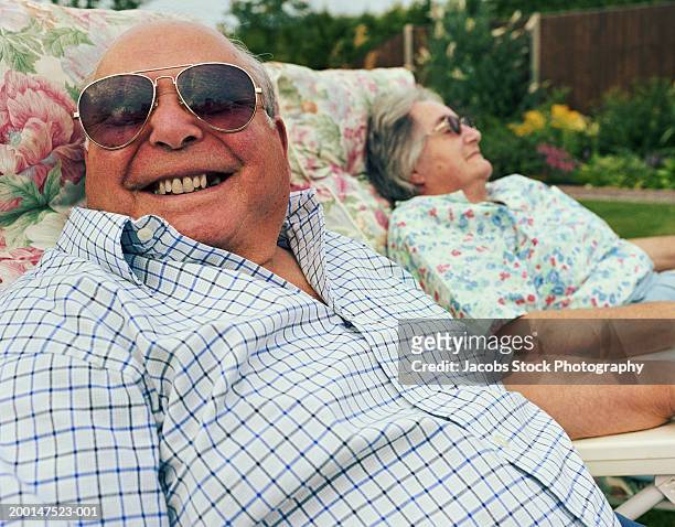 Senior couple relaxing on garden chairs (focus on man in foreground)
