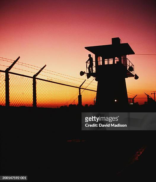 prison guard on duty in security tower at sunset, silhouette - tour de guet photos et images de collection