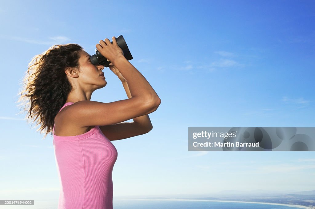 Woman looking through binoculars, side view