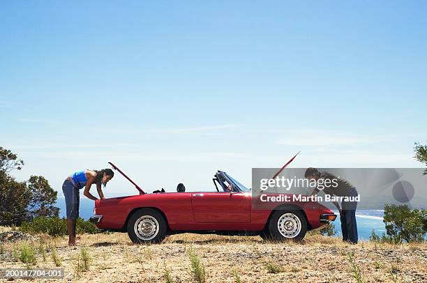 couple by convertible car looking in boot and bonnet, side view - crazy girlfriend stock pictures, royalty-free photos & images