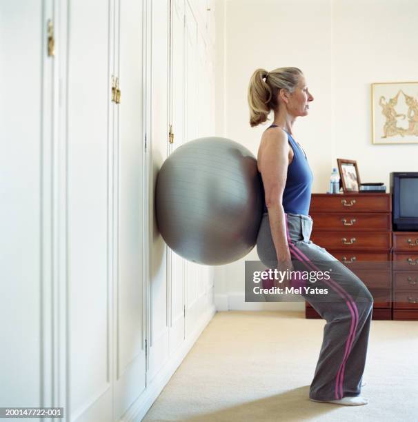 senior woman using exercise ball and dumb-bells, profile - fitness ball stock pictures, royalty-free photos & images