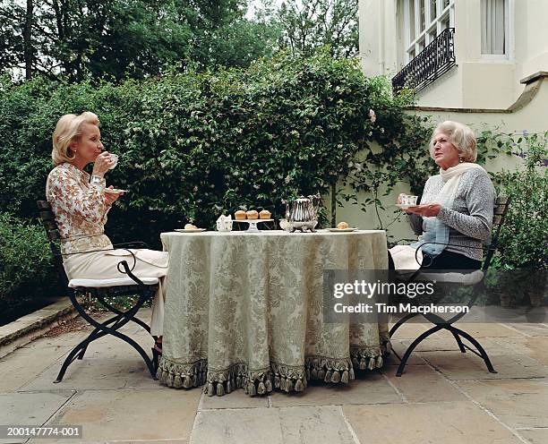 mature woman and senior woman having afternoon tea outdoors, side view - afternoon tea stock-fotos und bilder