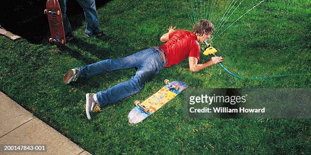 skateboarder drinking from sprinkler in front yard, elevated view - stoneplus4 stock pictures, royalty-free photos & images