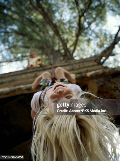 girl (6-8) hanging upside down from tree fort, low angle view - upside down stock pictures, royalty-free photos & images