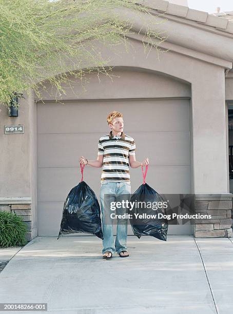teenage boy (16-18) holding two large garbage bags in driveway - domestic chores photos et images de collection