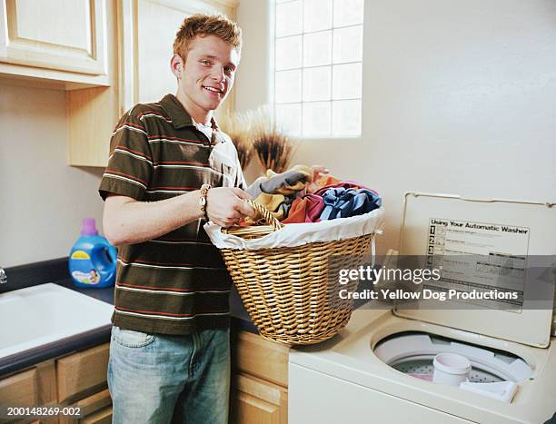 teenage boy (16-18) with basket of laundry, portrait - laundry basket stock pictures, royalty-free photos & images