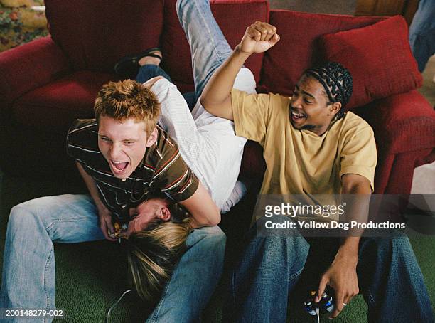 three young men play fighting on sofa - computer game fotografías e imágenes de stock