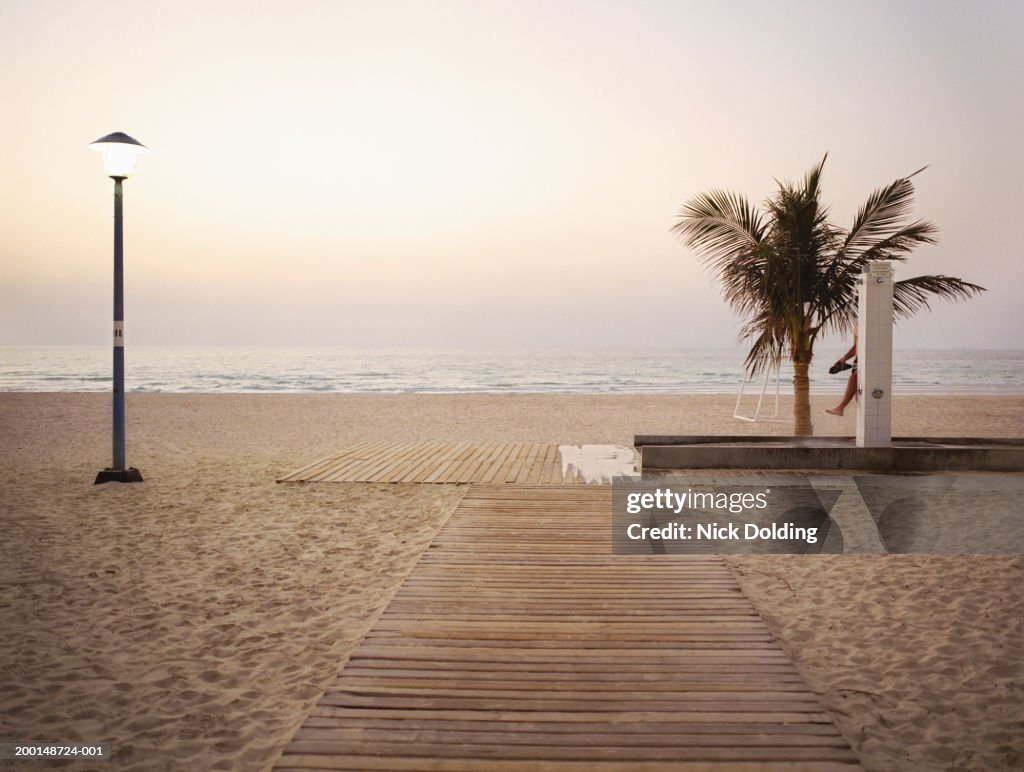 Man showering on beach, sunset