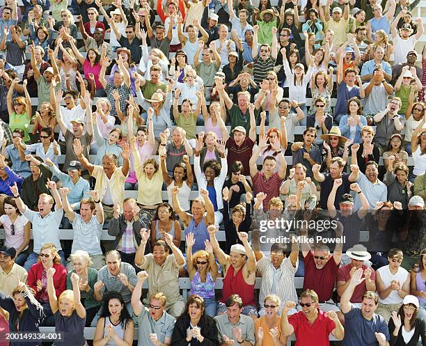 stadium crowd cheering, raising hands in air, elevated view - stadium crowd stock-fotos und bilder