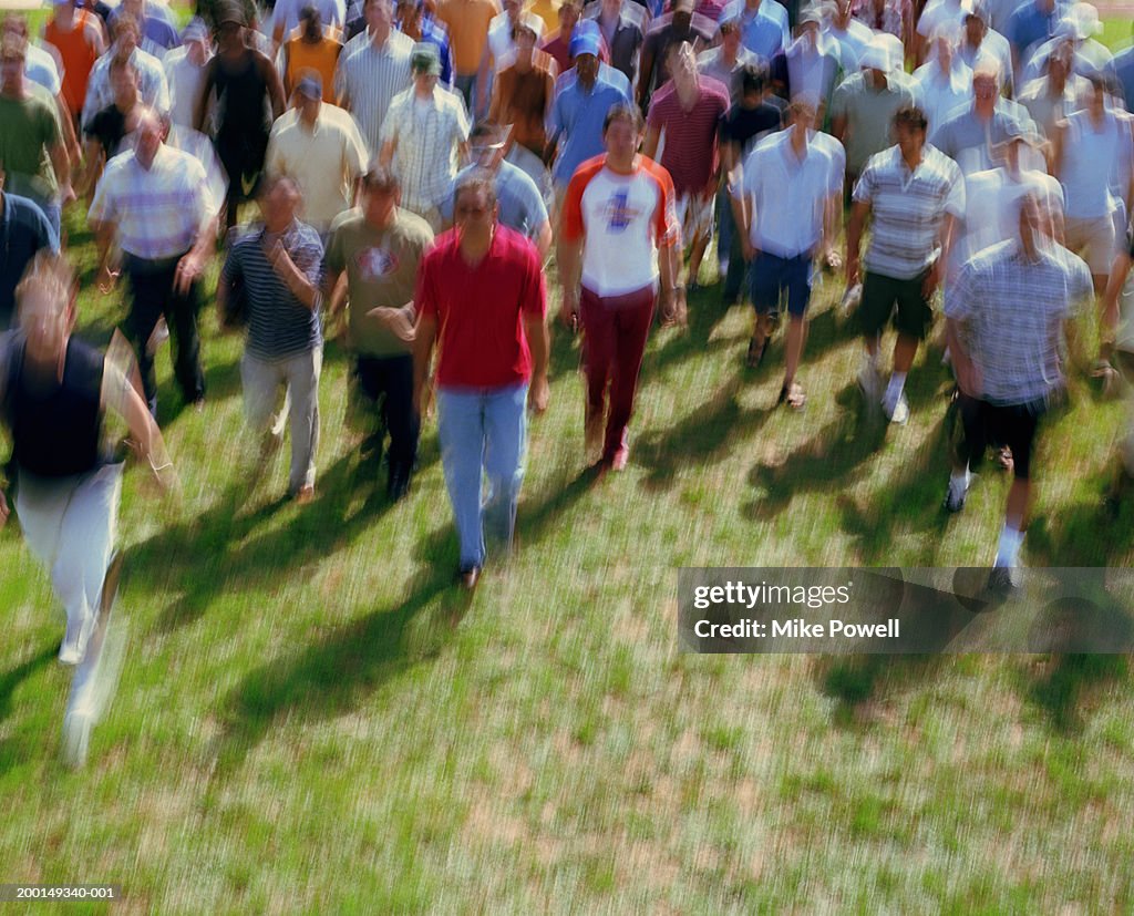 Crowd of men walking on grass, elevated view (blurred motion)