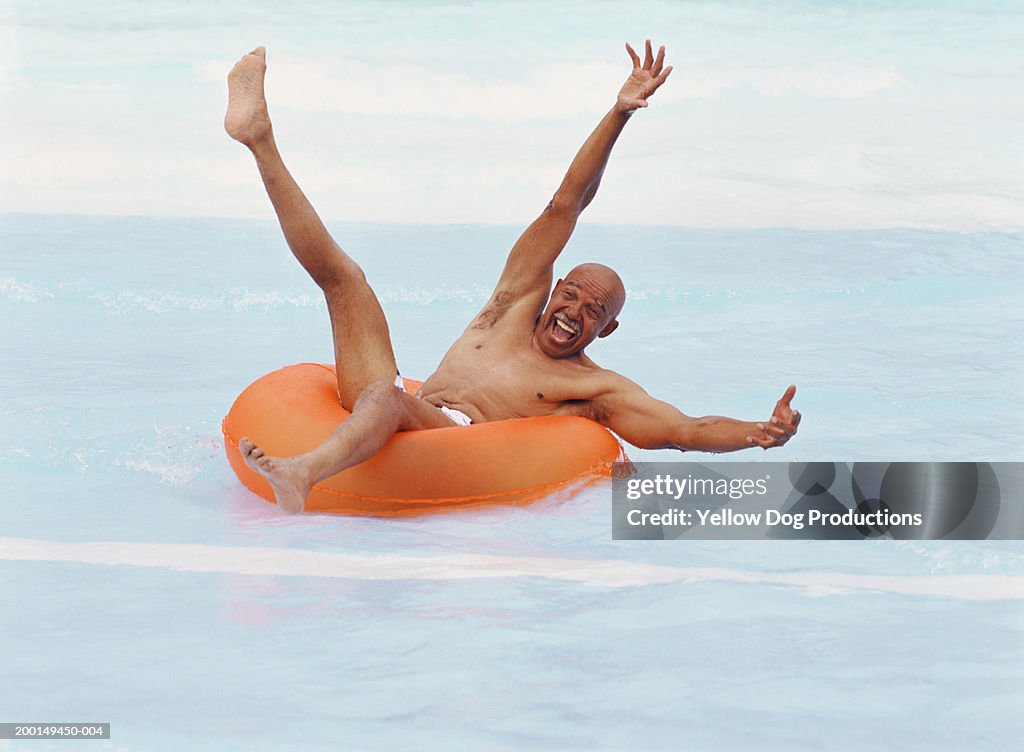 Senior man on plastic tube in water smiling