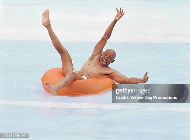 senior man on plastic tube in water smiling - water slide stock pictures, royalty-free photos & images