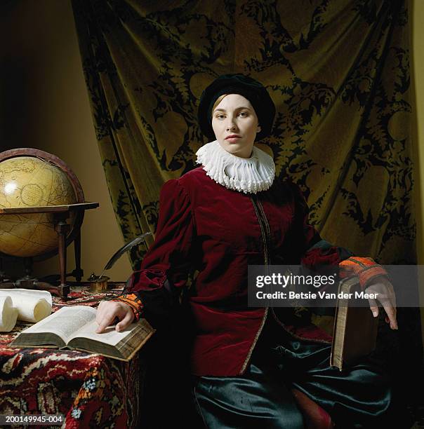 young woman wearing scholar outfit at desk, portrait - elizabethaanse stijl stockfoto's en -beelden