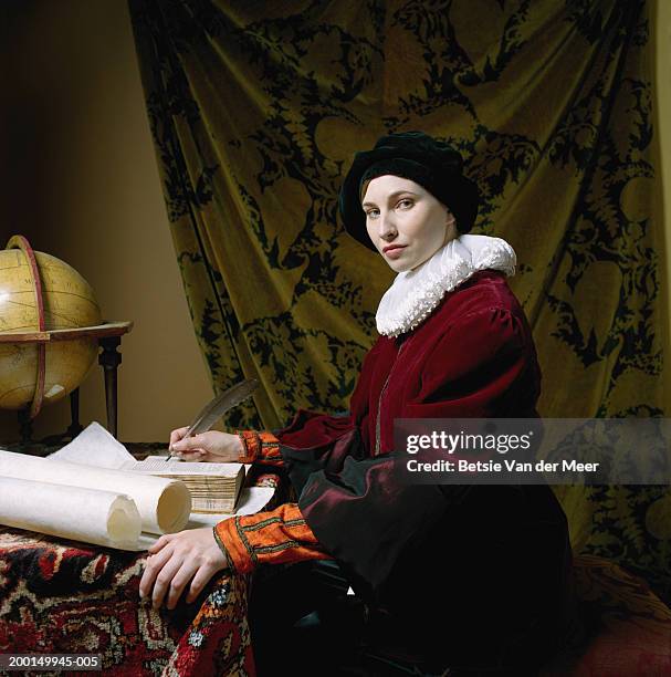 woman in scholar outfit, holding feather quill pen at desk, portrait - ひだ飾り ストックフォトと画像