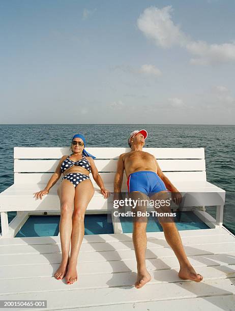 mature couple reclining in chair on jetty - old woman in swimsuit stock-fotos und bilder
